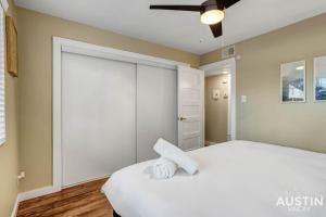 a bedroom with a white bed and a ceiling fan at Get Comfy Memory Foam Beds and Tub in Central ATX in Austin