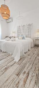 a white bedroom with a white bed and wooden floors at Villa O Canto da Parra - Swimming Pool - WIFI - BY BEDZY in Galé