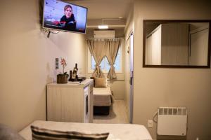 a room with two beds and a tv on the wall at Hospedagem Vila Suiça Centro in Gramado