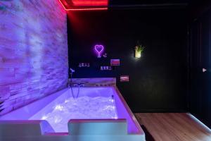 a bath tub in a room with a purple lighting at LOVE ROOM ou pas ! Chamalières in Chamalières