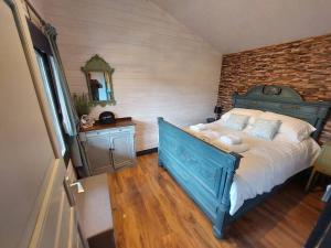 een slaapkamer met een blauw bed en een bakstenen muur bij The Malvern Hills, Courtyard Cabins,Tom Cabin in Great Malvern