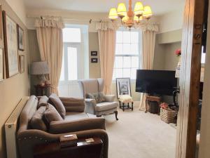 a living room with a couch and chairs and a television at Garden Cottage in Wetherby