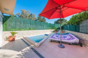 um guarda-sol vermelho sentado num pátio ao lado de uma piscina em 3 bedrooms house with private pool and enclosed garden at Puerto de Alcudia 1 km away from the beach em Port d'Alcudia