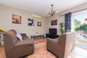 a living room with two chairs and a television at 3 bedrooms house with private pool and enclosed garden at Puerto de Alcudia 1 km away from the beach in Port d'Alcudia