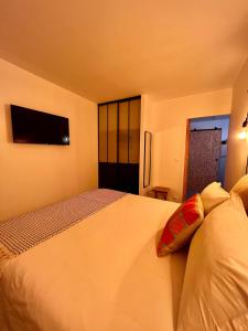 Senteurs du Maquis في بورتيكيو: غرفة نوم مع سرير أبيض كبير مع تلفزيون على الحائط