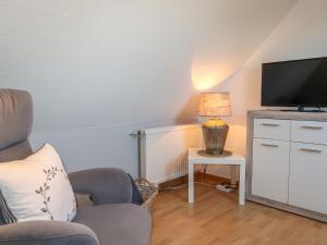 a living room with a tv and a chair at Apartment Rosenboom by Interhome in Wiarden