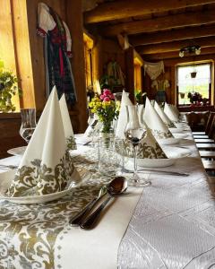 una mesa larga con platos blancos y servilletas. en Penzión Dinda en Stará Ľubovňa