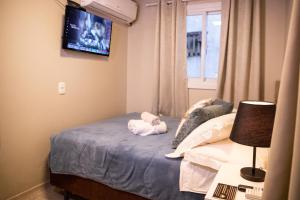 a bedroom with a bed and a tv on the wall at Hospedagem Vila Suiça Centro in Gramado