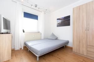 Dieses weiße Zimmer verfügt über ein Bett und einen TV. in der Unterkunft Strandnixe 301 in Döse