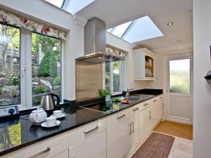 a kitchen with white cabinets and a sink and windows at Bishopsgate in Torquay