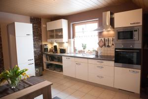 een keuken met witte kasten, een wastafel en een raam bij Ferienwohnung Am Korretsberg in Kruft
