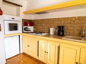 トゥレットにあるHoliday Home La Foux - TUR120 by Interhomeのキッチン(黄色のキャビネット、白い電子レンジ付)