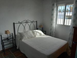una camera da letto con un letto con lenzuola bianche e una finestra di Apartamentos Cala Isabel a Zahora