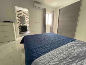 um quarto com uma cama azul e uma grande janela em 2 bedroom Apartment in Mellieha with Sea Views and Close to all Amenities em Mellieħa