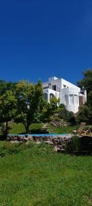 a large white house on top of a green field at La Flor del Camino Posada in Tanti +51 photos