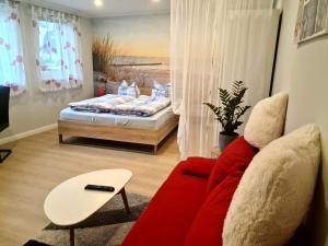un soggiorno con divano rosso e letto di Ferienappartement Ückeritz Usedom a Ueckeritz