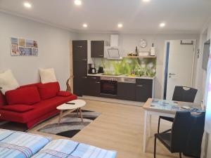 a living room with a red couch and a kitchen at Ferienappartement Ückeritz Usedom in Ueckeritz