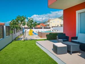 een balkon met een tuin met een bank en gras bij Holiday Home QUEEN AHN - SPY250 by Interhome in Kaštela