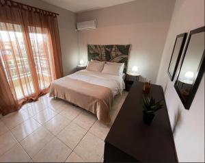 a bedroom with a bed and a table and a window at Raise Mirivili Serviced Apartment in Alexandroupoli
