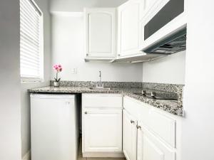 a white kitchen with white cabinets and a sink at The Flamingo in Hollywood