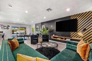 a living room with a green couch and a flat screen tv at The Ritz - Luxury Home with Pool & Speakeasy Bar in Palm Springs