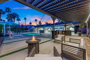 un patio al aire libre con bancos y una mesa con hoguera en The Ritz - Luxury Home with Pool & Speakeasy Bar, en Palm Springs