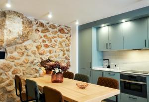 cocina con mesa de madera y pared de piedra en LIGNUM Casa Rural, en Ayna