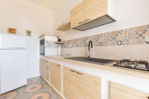 una cocina con armarios de madera y fregadero en Salentoandmore - Casa Anna, en Salve