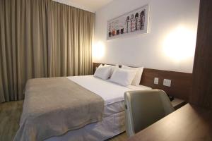 um quarto de hotel com uma cama e uma cadeira em Samba Linhares em Linhares