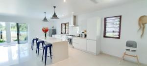 a white kitchen with white cabinets and blue chairs at Paradise Point Escape in Port Vila