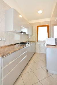 cocina con armarios blancos y encimera en Apartment Villaggio Delfino-2 by Interhome, en Bibione