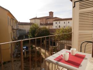 Un balcón con una mesa con dos tazas. en L' estate di san Martino Room Rental - free park, en Asti