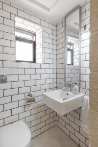 Baño blanco con lavabo y espejo en Roam Gozo - Studio Hamrija - Modern Cozy Tiny Home Set In Gozo's Oldest Village, en Xewkija