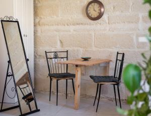 una mesa de madera con 2 sillas y un reloj en la pared en Roam Gozo - Studio Hamrija - Modern Cozy Tiny Home Set In Gozo's Oldest Village, en Xewkija