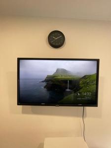 TV a schermo piatto appesa a un muro con orologio di Pension Hammer a Mensfelden