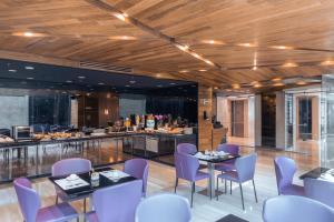 a restaurant with purple chairs and tables and a bar at Exe Oriental Panamá in Panama City