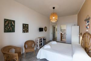 una camera con un letto bianco e due sedie di Brezza Marina a Tropea