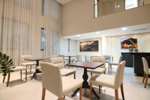 a waiting room with tables and white chairs at Samba Linhares in Linhares