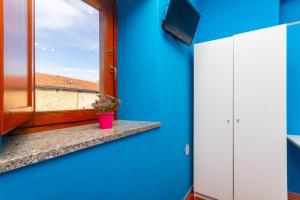 una camera blu con finestra e una pianta in vaso di Affittacamere Grugliasco Ressia a Grugliasco