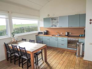 een keuken met een tafel en stoelen en een keuken met blauwe kasten bij Holiday Home Lauwersmeer - LWM101 by Interhome in Oostmahorn