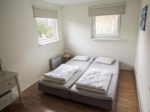 twee bedden in een kleine kamer met twee ramen bij Holiday Home Lauwersmeer - LWM101 by Interhome in Oostmahorn