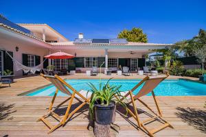 een huis met een zwembad en twee stoelen bij Spacious villa in Sesimbra with a private year-round pool in Sesimbra