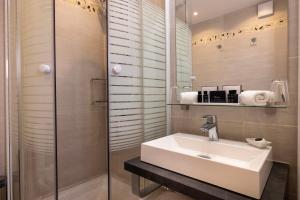 La salle de bains est pourvue d'un lavabo et d'une douche en verre. dans l'établissement Relais Hôtel du Vieux Paris, à Paris