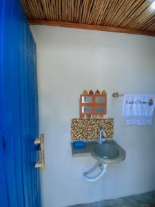 a bathroom with a sink and a blue shower curtain at Beira-mar Chácara Curimãs - Barroquinha, Ceará in Barroquinha
