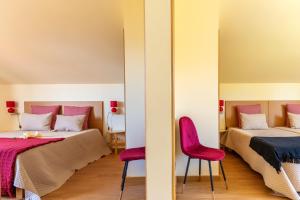 una camera con due letti e due sedie rosa di Comfortable apartment with shared pool in Prazeres, 150 m² a Campanário