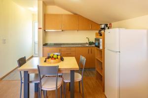 a kitchen with a table and a white refrigerator at 2 bedrooms apartement with shared pool enclosed garden and wifi at Prazeres 5 km away from the beach in Campanário