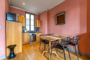 cocina y comedor con mesa de madera y sillas en Magnifique appartement en Hypercentre, en Burdeos