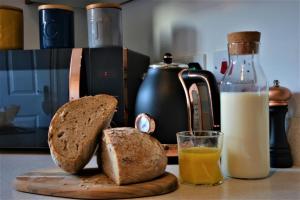 a cutting board with bread and a glass of orange juice at Peaceful, Lovely and Modern, Entire House in Edinburgh