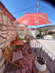 un patio con una mesa y una sombrilla roja en Apartman Lidija, en Makarska