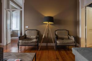 uma sala de estar com duas cadeiras e um candeeiro de chão em Central São Paulo by Lisbon Heart em Lisboa